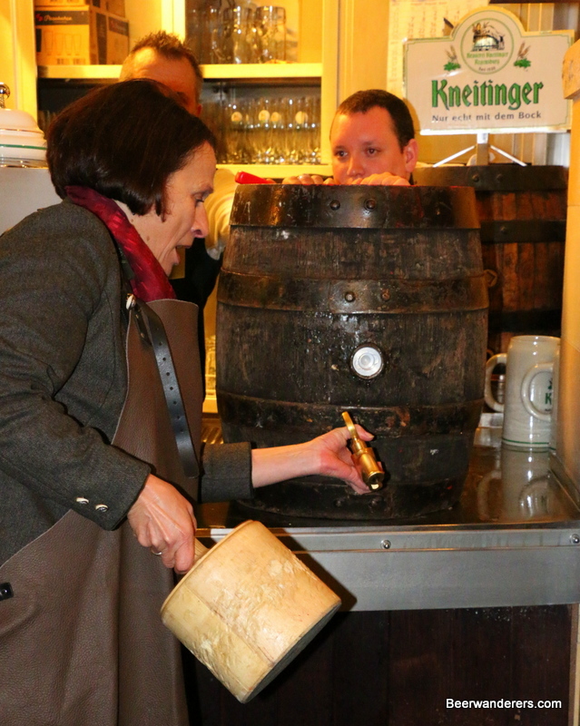 woman taps wooden beer barrel