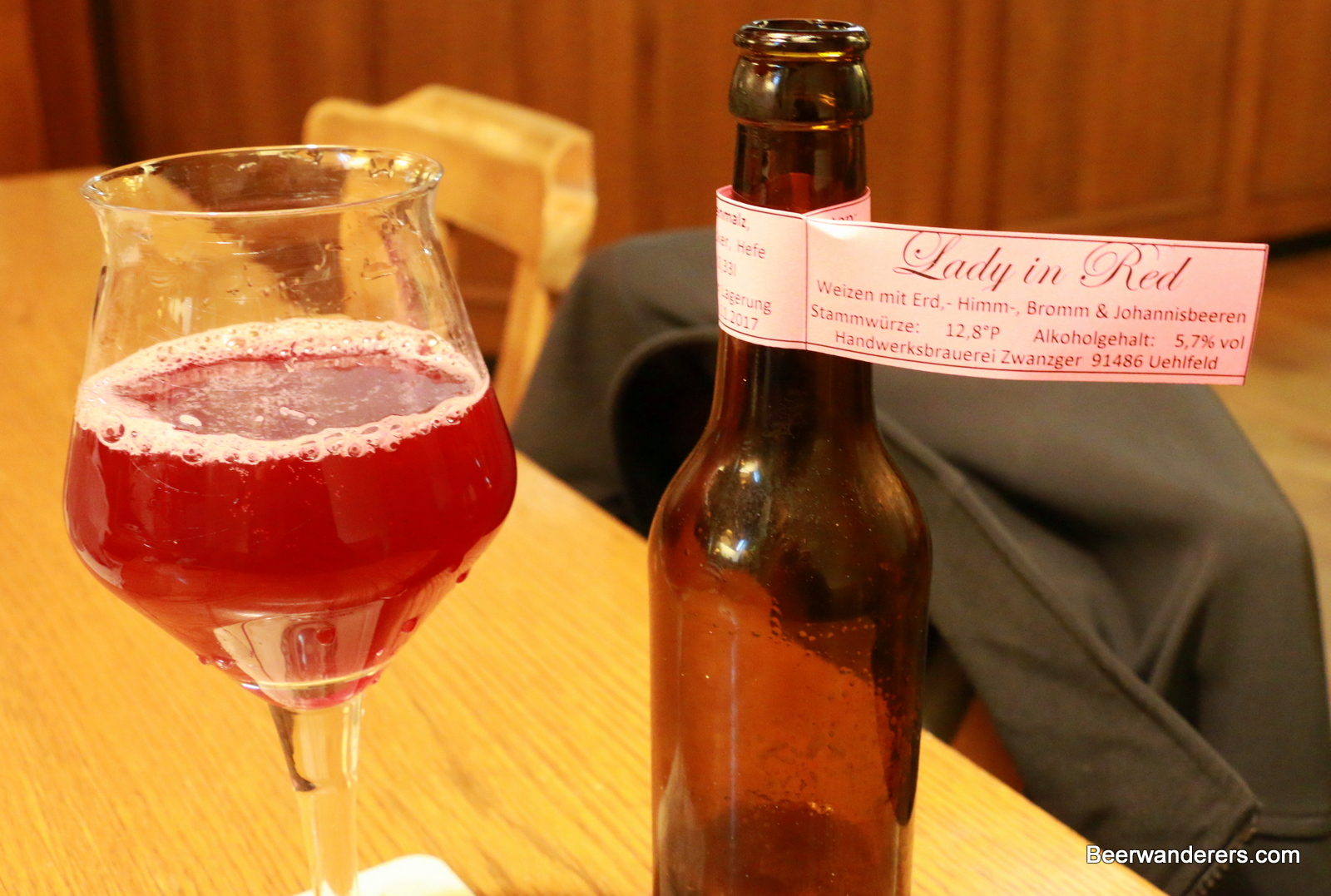 pink beer in glass with bottle