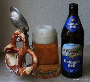 golden beer in lidded mug with pretzel and bottle
