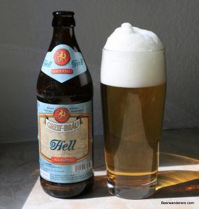golden beer with huge head in glass with bottle