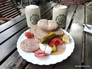 cold cuts with bread and two beers in ceramic mugs